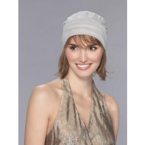 Vrouw draagt het Verbena haarstuk van Ellen Wille – halflang echt haar met pony onder een lichte muts.