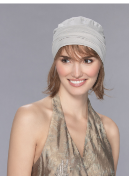 Vrouw draagt het Verbena haarstuk van Ellen Wille – halflang echt haar met pony onder een lichte muts.